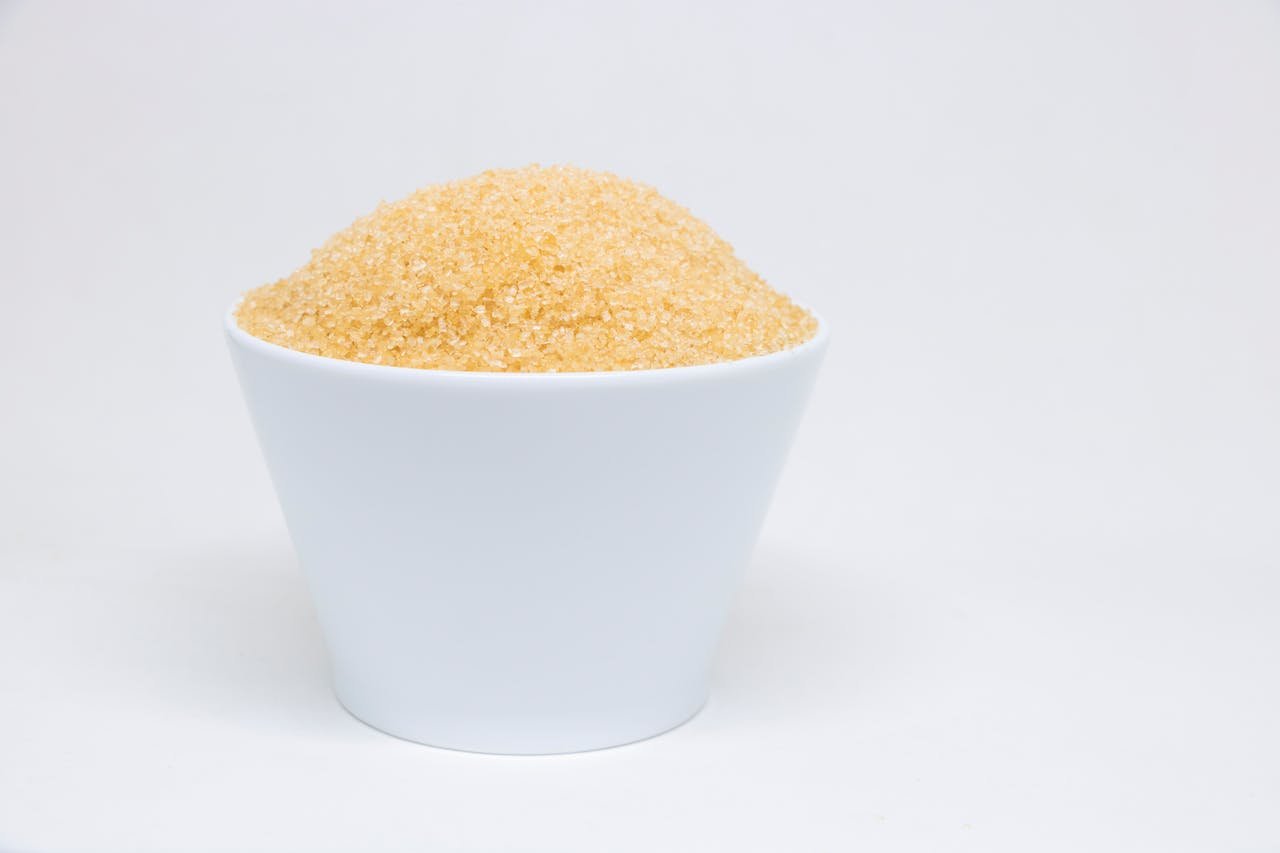 A white bowl filled with brown sugar against a clean, white background.