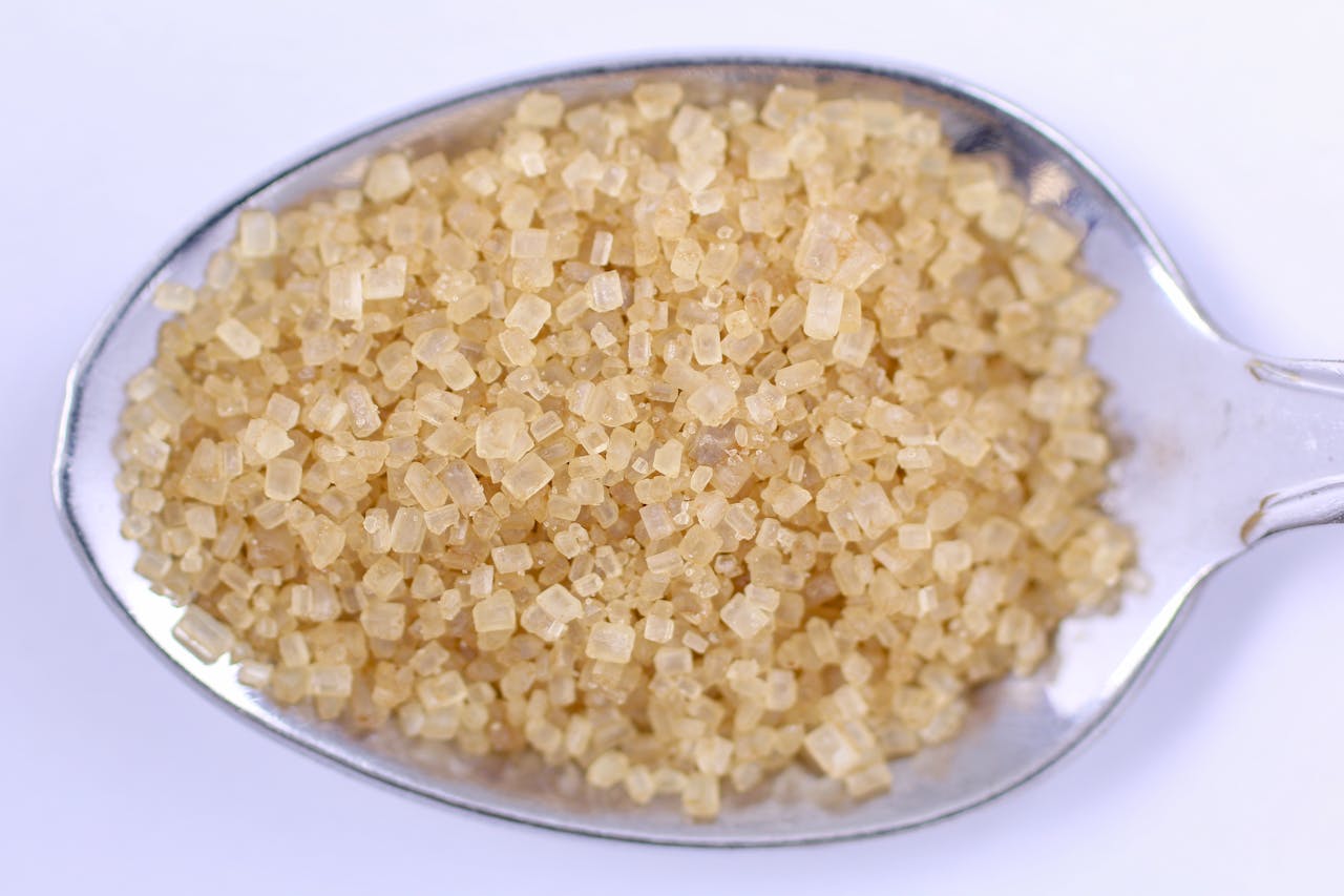 Detailed close-up of raw brown sugar on a metal spoon, perfect for food and cooking themes.
